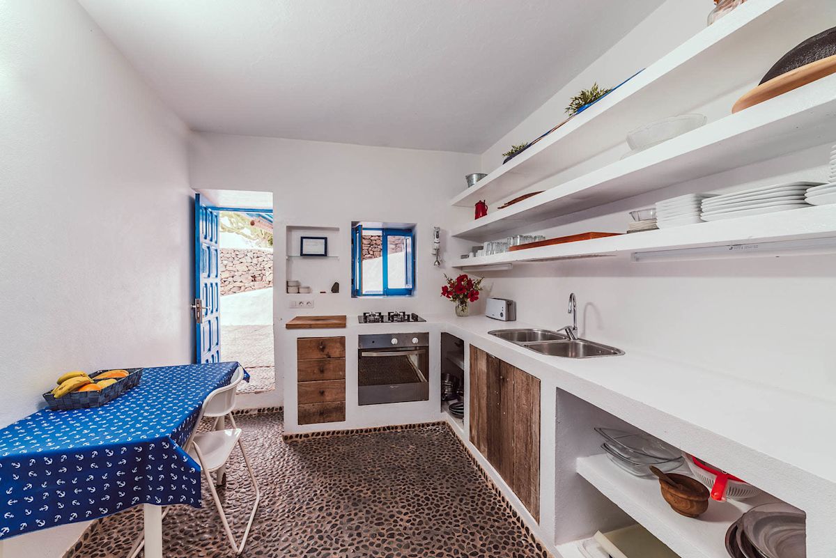 Cocina con estanterías blancas y mesa con mantel azul