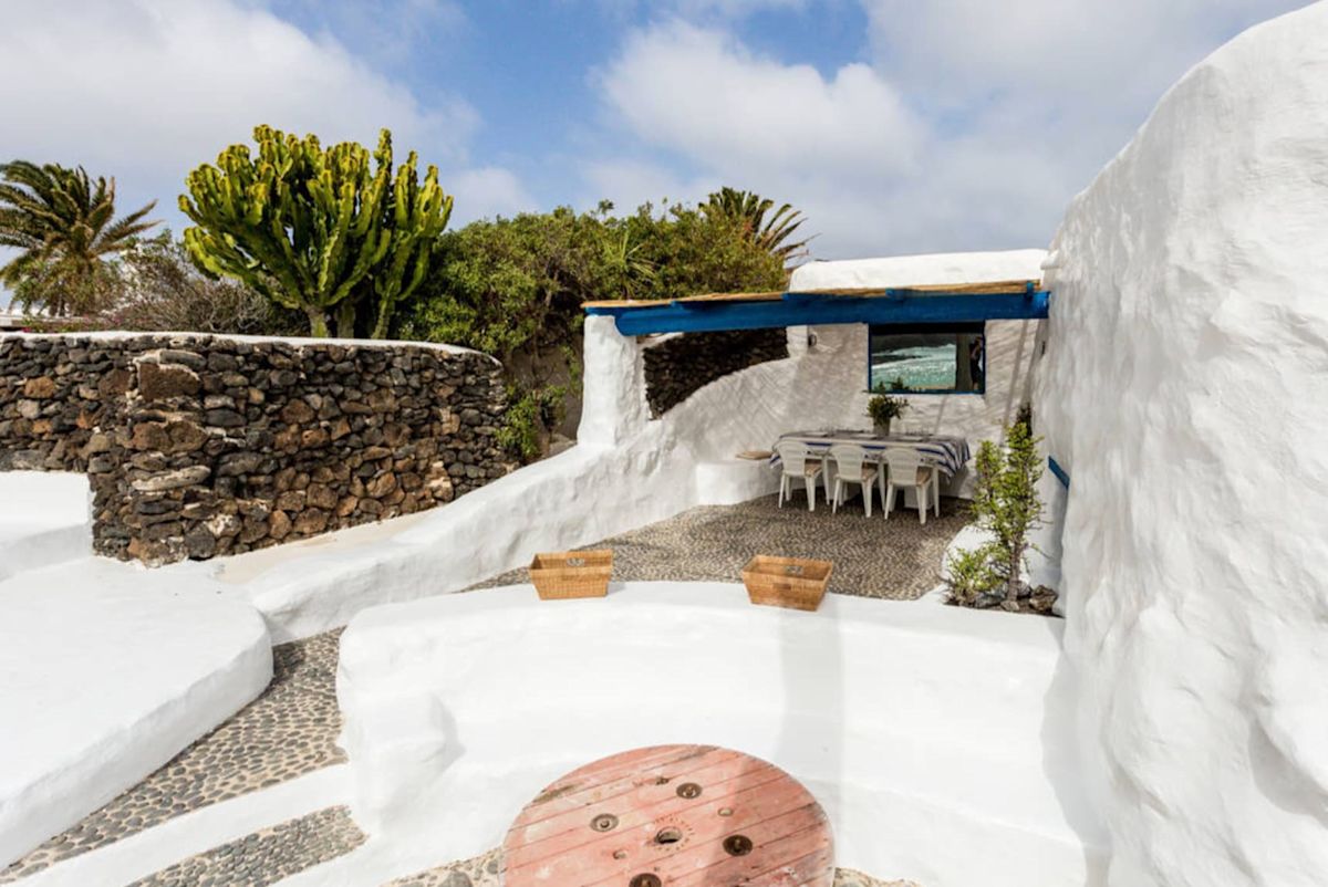 Terraza encalada con pérgola y muros de piedra volcánica