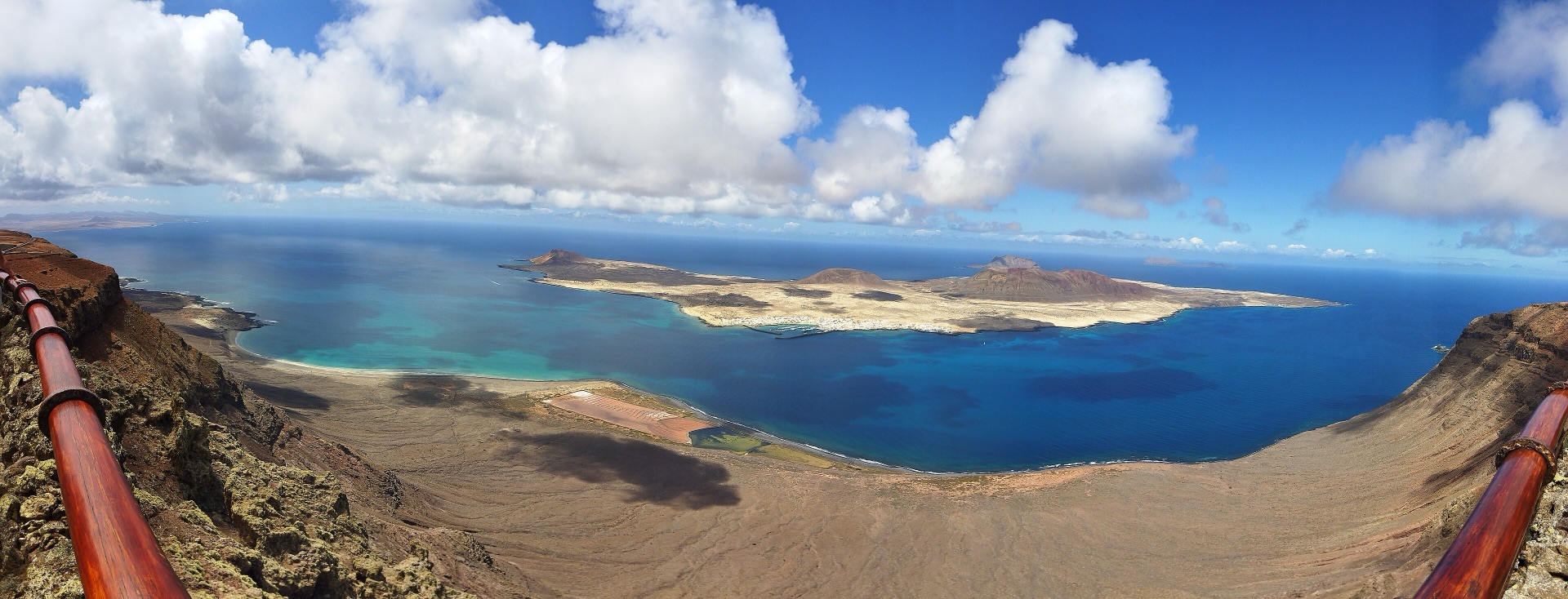 La Graciosa vista desde el Mirador del Río, con El Río turquesa y nubes de verano