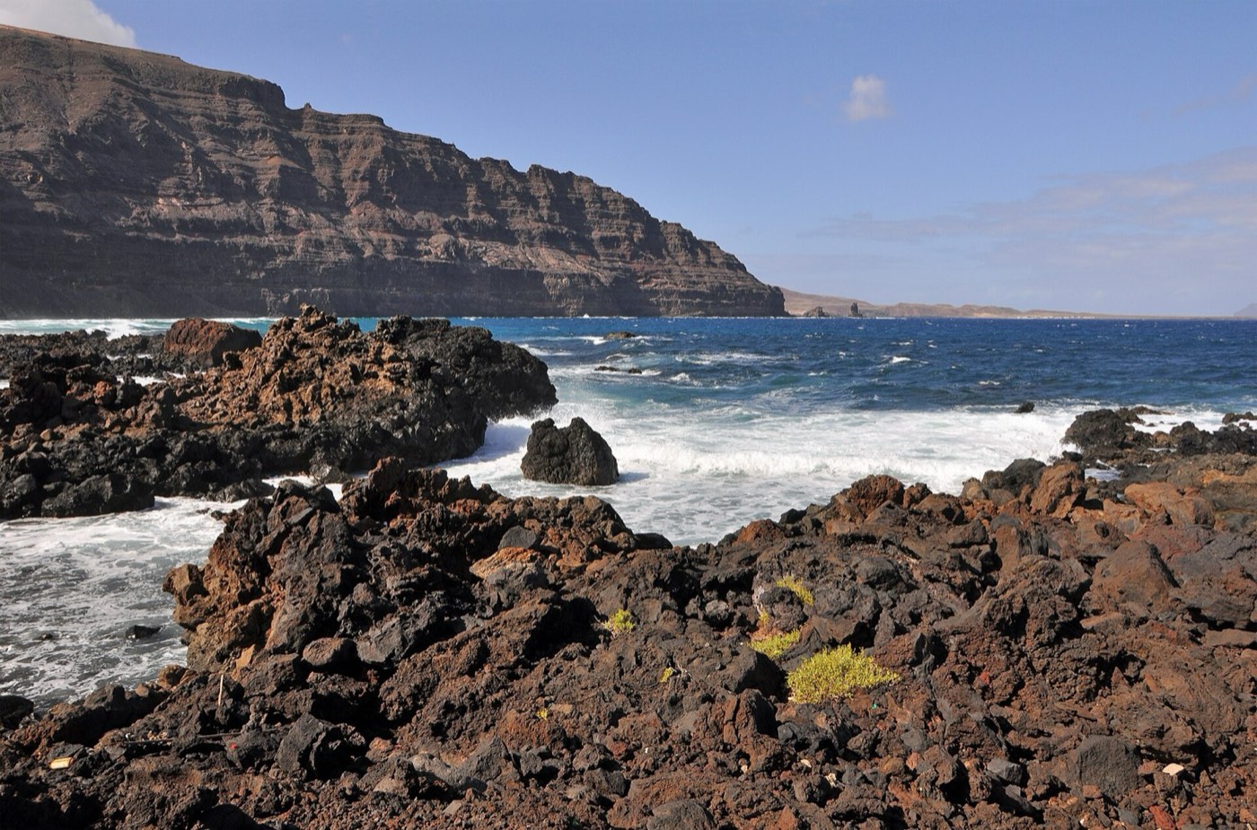 Costa de lava de Órzola con el Risco de Famara al fondo